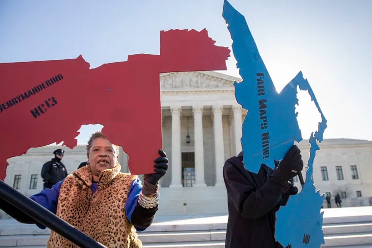 Activists at the Supreme Court opposed to partisan gerrymandering hold up representations of congressional districts from North Carolina, left, and Maryland, right, as justices hear arguments about the practice of political parties manipulating the boundary of a congressional district to unfairly benefit one party over another, in Washington, Tuesday, March 26, 2019.