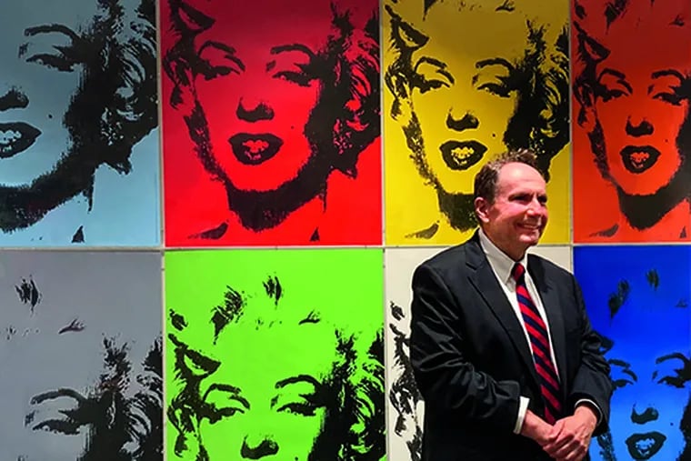 Collector Gregory McCoy standing in front of a grid of his Marilyn screen prints at the opening of the "Out of Sight" exhibition.