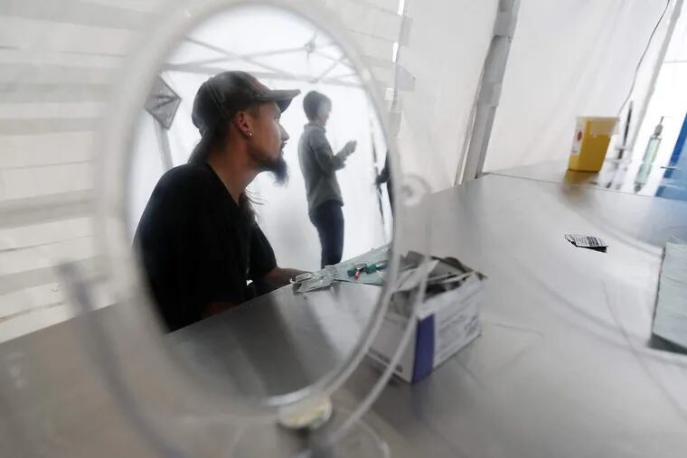 Heroin user Robert Johnson is reflected in a mirror inside the tent at the pop-up safe injection site at Moss Park in Toronto, Canada.