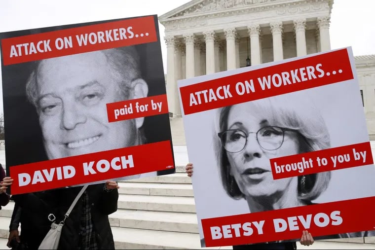 Members of the American Federation of Teachers hold up signs depicting Education Secretary Betsy DeVos and Koch Brother, David Koch, while protesting in support of unions outside of the Supreme Court, Monday, Feb. 26, 2018, in Washington. The Supreme Court takes up a challenge in a case that could deal a painful financial blow to organized labor. The court is considering a challenge to an Illinois law that allows unions representing government employees to collect fees from workers who choose not to join.