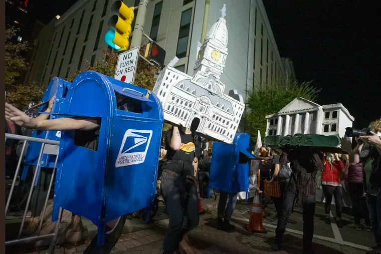 A mailbox, City Hall, and the White House puppets — all made by Spiral Q — dance together by Biden supporters on Nov. 5, 2020, outside of the Pennsylvania Convention Center. The mailbox puppet is now going into the Smithsonian's National Museum of American History.