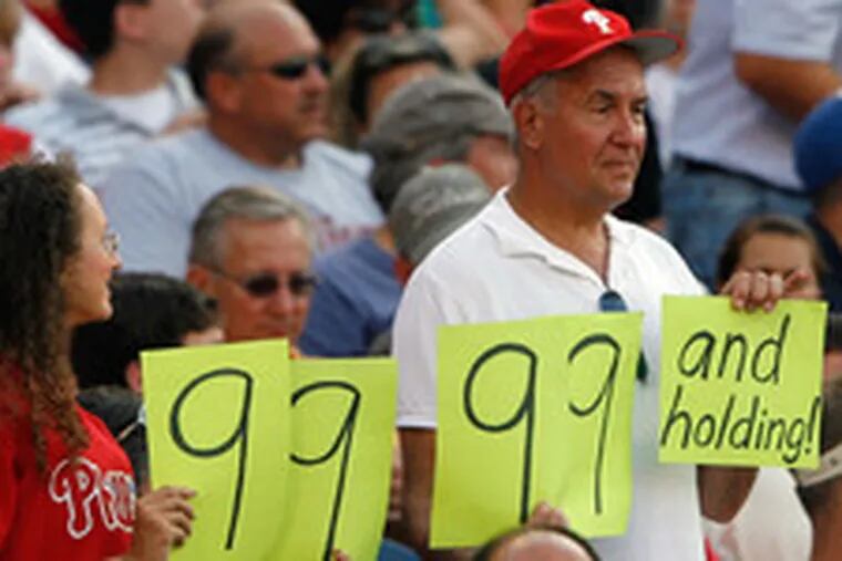 Fans hold up cards indicating that the Phillies have 9,999 losses and holding, still one away from the not-so-magical 10,000 mark.