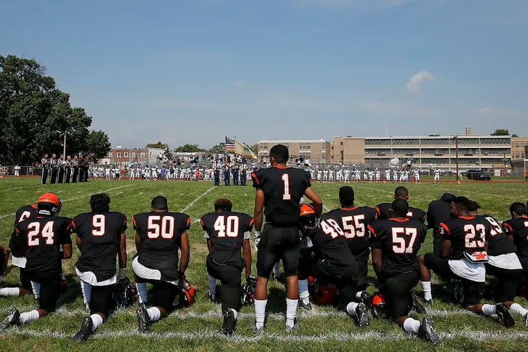 Woodrow Wilson High School football coach Preston Brown and his coaching staff, along with most of his players, kneel while the national anthem is played before their game on Sept. 10.