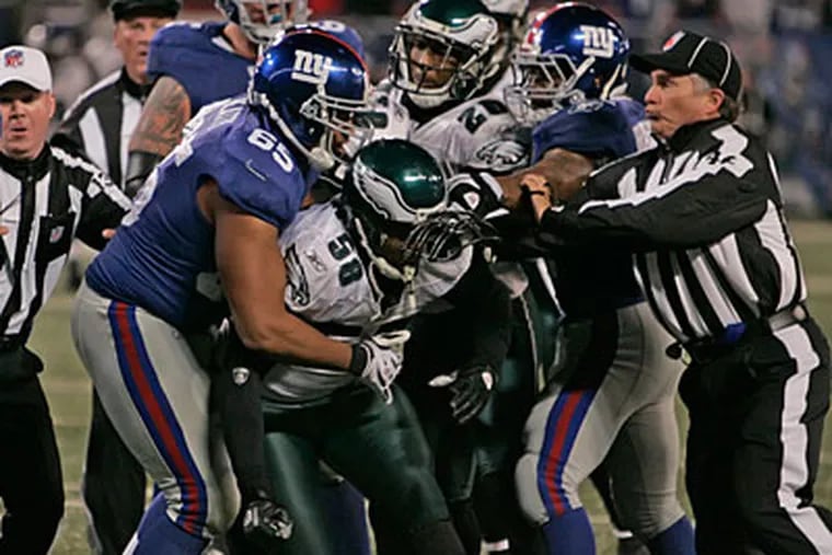 Trent Cole is grabbed as officials try to break up the end-of-game scuffle. (Michael Bryant/Staff Photographer)