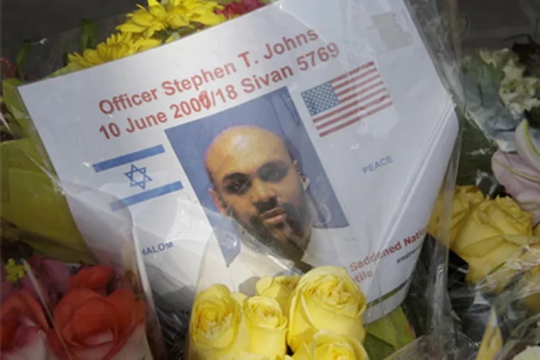 A picture of guard Stephen T. Johns , slain by a man who burst into the U.S. Holocaust Museum in Washington, was placed with flowers near the museum on Friday. (Alex Brandon / AP)