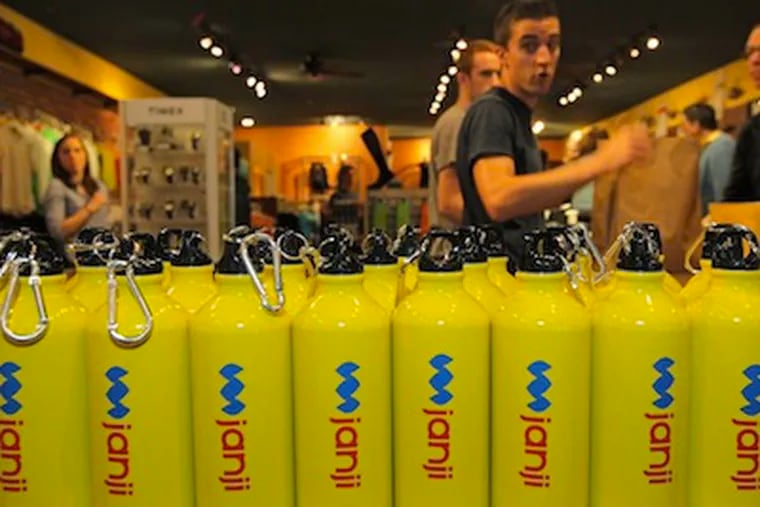 Water bottles with the Janji company logo sit by the register as customers line up to purchase the running apparel. David Spandorfer has created a line of running apparel to raise funds for needy countries like Haiti and Kenya. They are being sold at Bryn Mawr Running Company in Bryn Mawr.  ( MICHAEL BRYANT / Staff Photographer )
