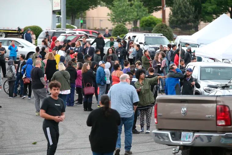 Students gather outside Parkrose High School  during a lockdown after a man armed with a gun was wrestled to the ground by a staff member, Friday, May 17, 2019 in Portland, Ore. The Portland Police Bureau said in a statement Friday that no shots were fired at Parkrose High School, no one was injured and the man is in custody. Police say there are no other suspects.