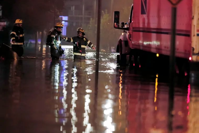 Standing in floodwaters, Philadelphia firefighters stop a USPS truck from driving down North 23rd Street at Race Street, just before 5 a.m. on Sept. 2, hours after the remnants of Hurricane Ida hit. Officials said residents should remember never to drive into standing water.