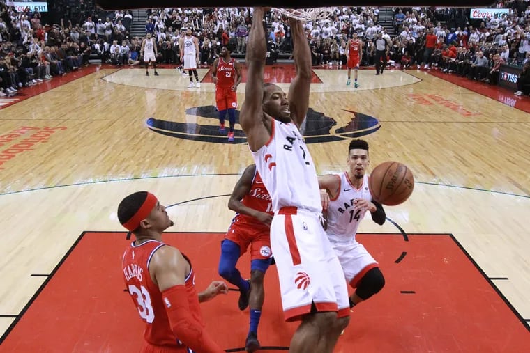 Kawhi Leonard, center, of the Raptors dunks over Tobias Harris, left, during 1st half action in game 7 of the NBA Eastern Conference semifinals at the Scotiabank Arena in Toronto on May12, 2019.