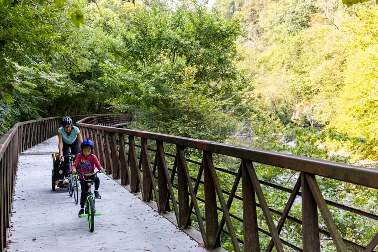 Ezra Nguyen, 8, of Roxborough, Pa., is with her mom Michelle Nguyen, riding their bikes on the newly reopened trail bridge in the Wissahickon Valley Trails in Philadelphia, Pa., Friday, Sept., 16, 2022.