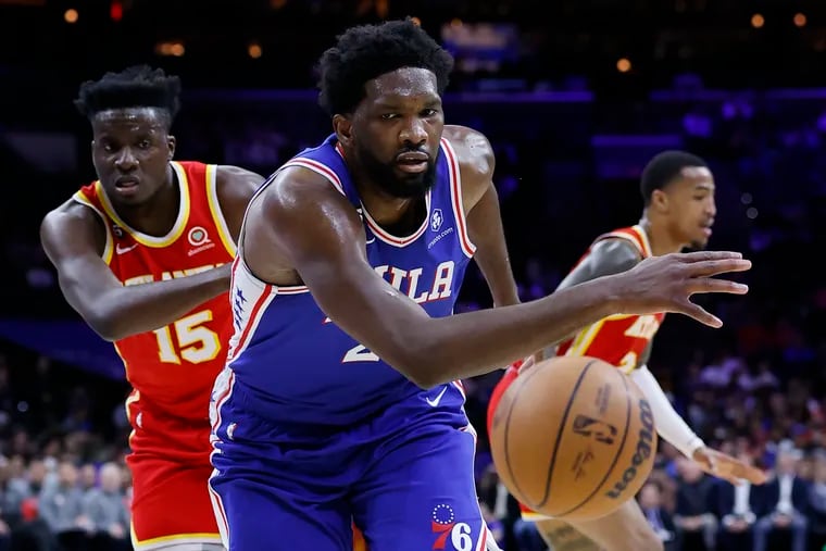 Sixers center Joel Embiid goes after the loose basketball past Atlanta Hawks center Clint Capela in the first quarter on Monday, November 28, 2022 in Philadelphia.