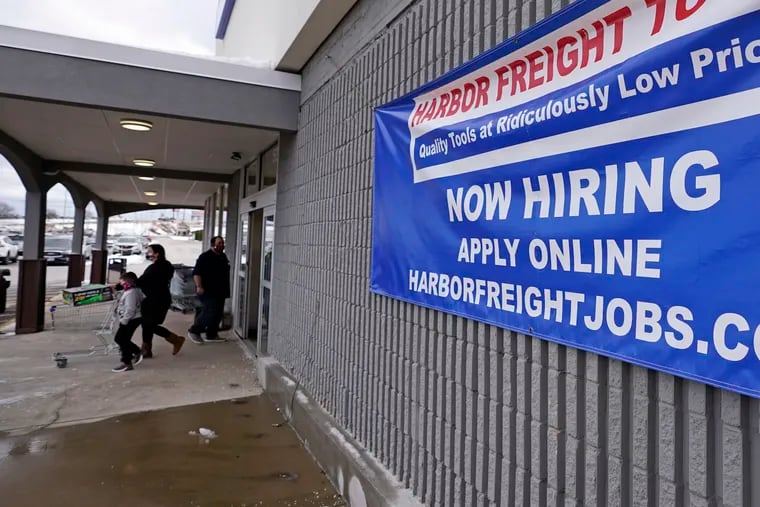 In this Dec. 10 photo, a "Now Hiring" sign hangs on the front wall of a Harbor Freight Tools store in Manchester, N.H.