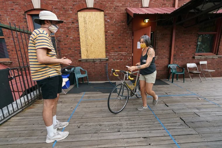 Monica Pasquinelli brings a bike out to a customer waiting outside on the deck at Firehouse Bicycles in Philadelphia.