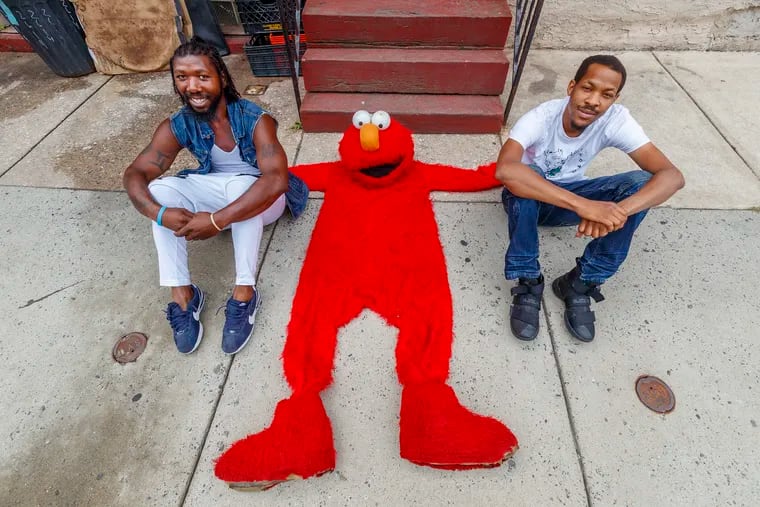 Tony Royster, left and Dontae Thomas, right, of the drill team Positive Movement, with the empty suit of their colleague William "Elmo" Fulton