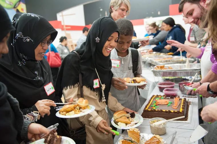 (From left) Khulood Salman, 16, Kantima Dangkhuntong, Huda Salman, 17, and Mohammad Salman, 13, who all immigrated to Philadelphia from Thailand two months ago, choose from the dessert offerings with the assistance
of volunteer Eric Haase, right, of Havertown, during the 11th annual Thanksgiving dinner to welcome new immigrants and refugees at the Nationalities Service Center in Philadelphia on Saturday.