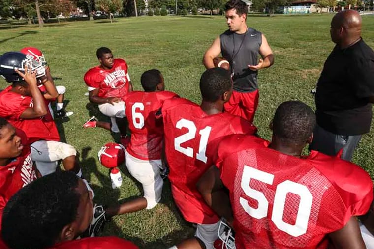 Head Coach Steve Quigley with assistant coach Derrick Lewis-El (at right) works with Strawberry Mansion HS football players on the first varsity football team in the school's 50 year history.