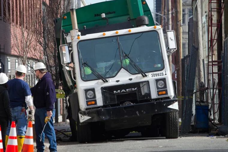 Philadelphia fire and police crews were called to the scene of a trash truck that got stuck in a pothole along the 1300 block of Kater St. in Center City Philadelphia on Monday, January 13, 2014. Two large tow trucks were brought it to pull it out. ( ALEJANDRO A. ALVAREZ / STAFF PHOTOGRAPHER )