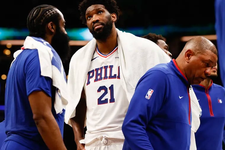 Joel Embiid (21) with James Harden and coach Doc Rivers commiserate late in the fourth quarter of a blowout Game 2 loss Wednesday in Boston.