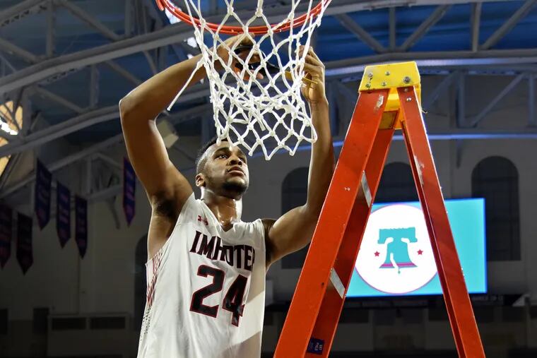 Imhotep's Donta Scott cuts a piece of the net after the Panthers won the Public League basketball championship game over Martin Luther King in February..