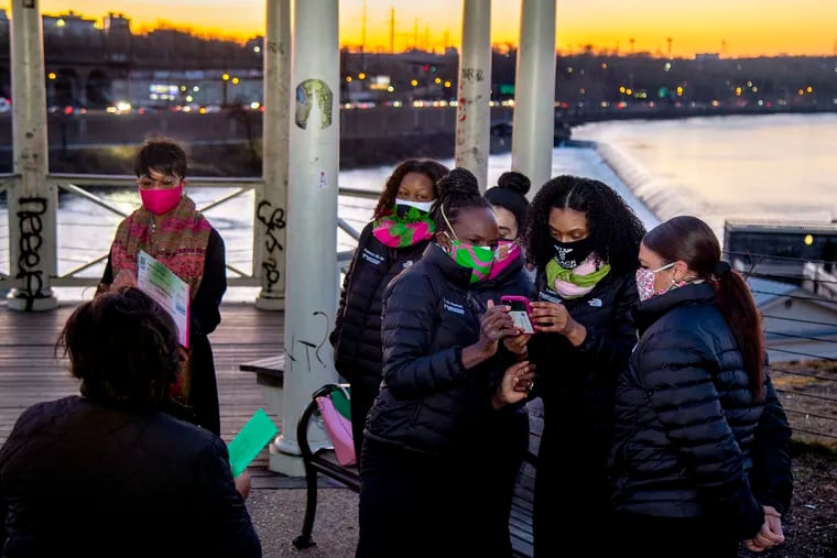 Ala Stanford (front, right), founder of the Black Doctors COVID-19 Consortium, gets her phone ready along with colleagues for pictures as Mary Bentley LaMar (left), North Atlantic Regional director of Alpha Kappa Alpha Sorority, prepares to present the group with a $25,000 donation on the gazebo overlooking the Schuylkill on Sunday.