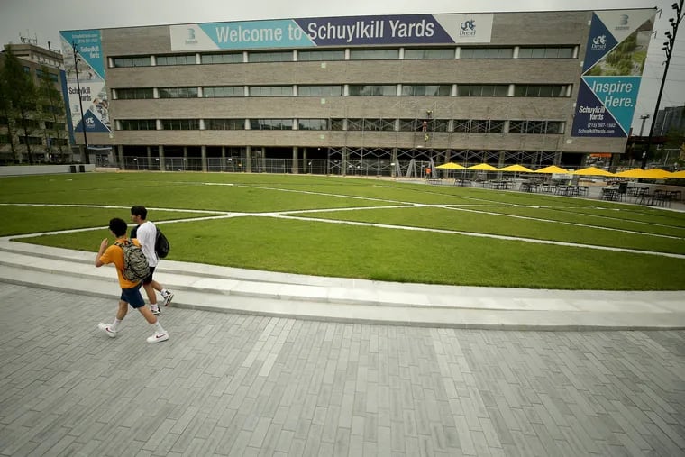 Pedestrians cross Drexel Square, a new privately built park that will form the centerpiece of Schuylkill Yards.