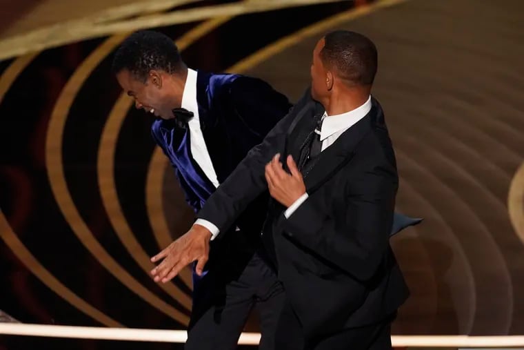 Will Smith, right, hits presenter Chris Rock on stage while presenting the award for best documentary feature at the Oscars on Sunday at the Dolby Theatre in Los Angeles.