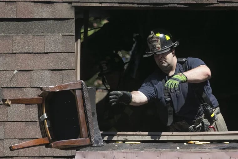 A firefighter clears debris from a charred section of the  Clifton Heights, Pa., apartment complex. The complex was hit by a multi-alarm fire that left several residents and a firefighter injured.