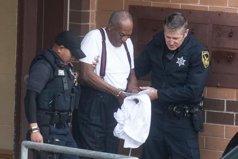 Bill Cosby is escorted by police in handcuffs as he exits the Montgomery County Correctional Facility in Norristown on Tuesday.