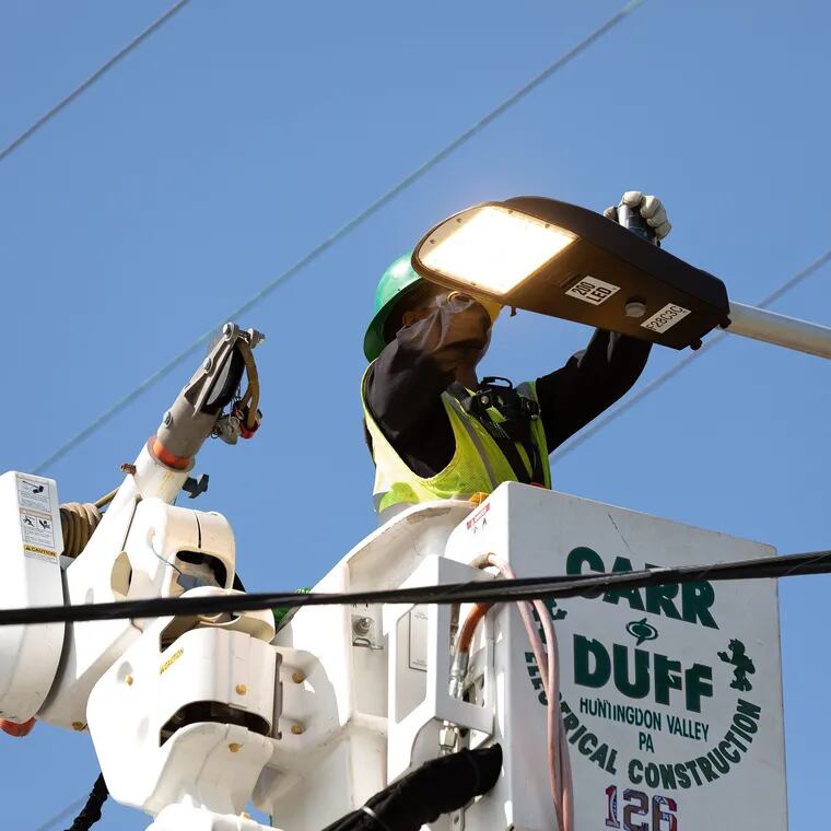 A local crew member tasked with installing new LED street lights across Philadelphia installs a fixture during the 2023 kick-off event for the Philadelphia Street Light Improvement Project.