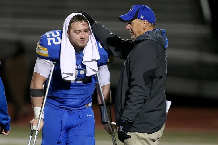 Sean Pelkisson of Downingtown West is comforted by head coach Mike Milano after their loss to Central Dauphin in the PIAA Class 6A semifinals on Friday.