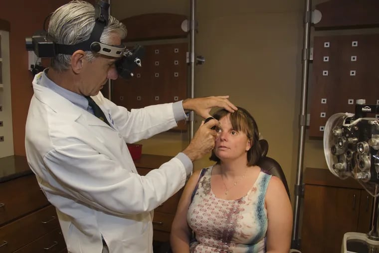 University of Pennsylvania eye surgeon Albert Maguire examines Stacy Young, who lost her left eye and became legally blind in her right eye from a fireworks injury in 2000.