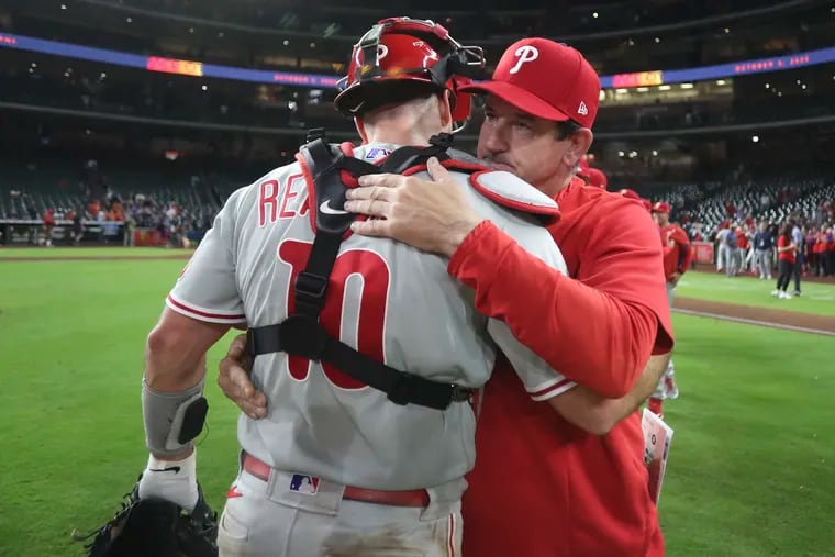 Interim manager Rob Thomson hugging catcher J.T. Realmuto after the Phillies beat the Houston Astros to clinch a playoff berth on Monday night.