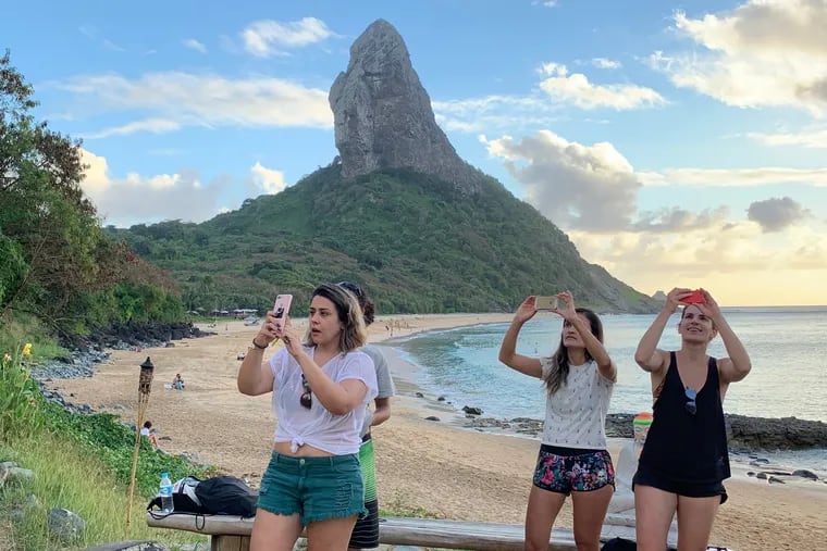 Tourists take pictures on a beach in Fernando de Noronha, Brazil.