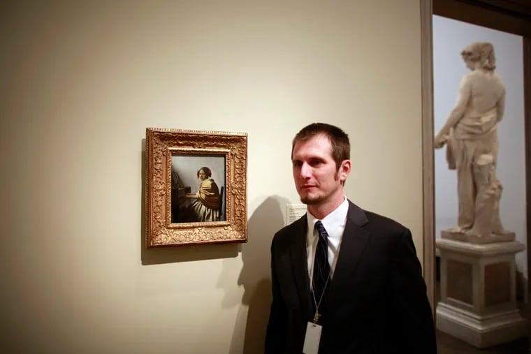 Curator Christopher Atkins stands close to Johannes Vermeer's "Young Woman Seated at a Virginal." The painting is hanging at the Philadelphia Art Museum for the second time in a decade. ( DAVID SWANSON / Staff Photographer )