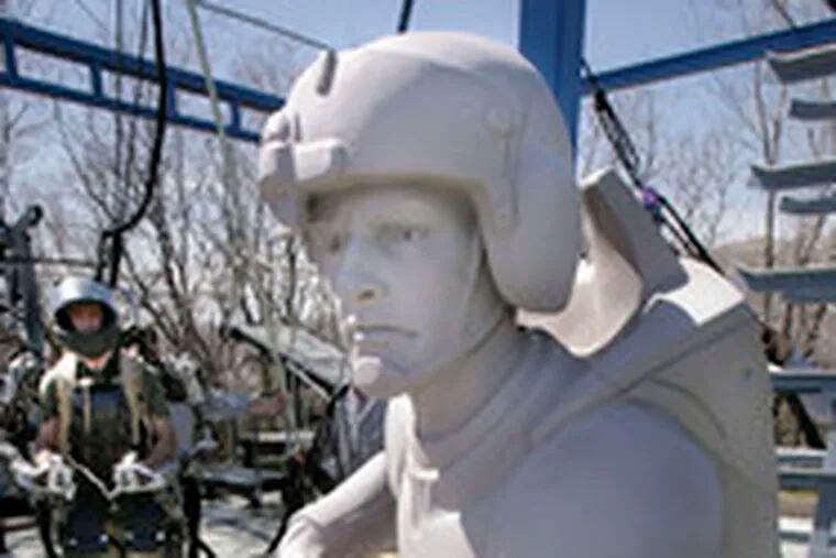 Software engineer Rex Jameson, wearing a robotic soldier suit being made for the U.S. Army, stands next to a mock-up statue of a future soldier in Salt Lake City, Utah.