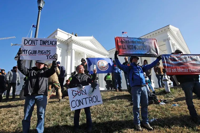FILE - This Monday Jan. 20, 2020 file photo shows pro-gun demonstrators holding signs in front of the Virginia State Capitol in Richmond, Va.