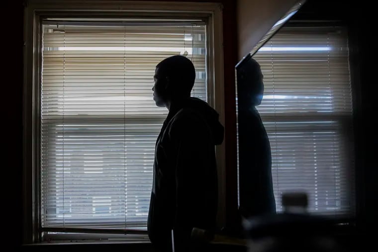 A.W., who asked to be identified by his initials, is silhouetted as he poses for a portrait in his bedroom in Philadelphia on Thursday, Feb. 14, 2019. A.W. was beaten up by counselors at Glen Mills Schools.