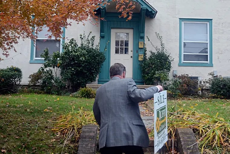 John Duffy puts up a for-sale sign at one of his listings in Narberth. TOM GRALISH / Staff Photographer