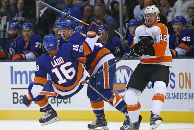 The Islanders’ Andrew Ladd (16) is upended by the stick belonging of Flyers left winger Michael Raffl (12) in Sunday’s preseason game.