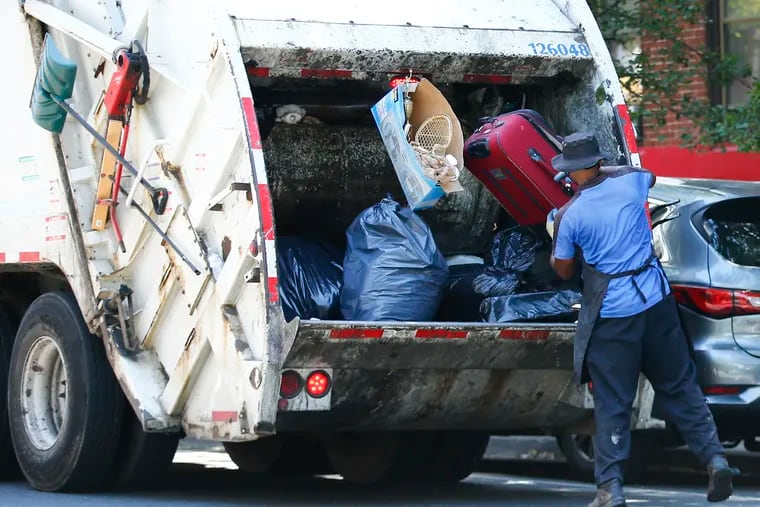 A city worker collects trash in North Philadelphia. The sanitation workers' union, AFSCME District Council 33, is hoping to include new worker safety guarantees in its next contract with the city.