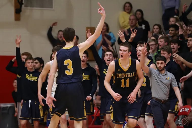 The Unionville team celebrates after Logan Shanahan, (No. 11) hit a three-pointer in the fourth of a 61-49 victory over West Chester Rustin.