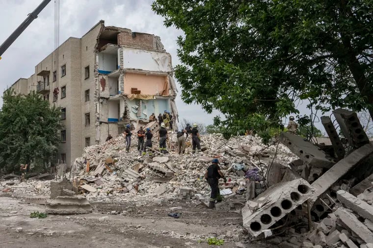 Rescue workers stand on the rubble at the scene in the after math of a missile strike that his a residential apartment block, in Chasiv Yar, Donetsk region, eastern Ukraine, Sunday, July 10, 2022.