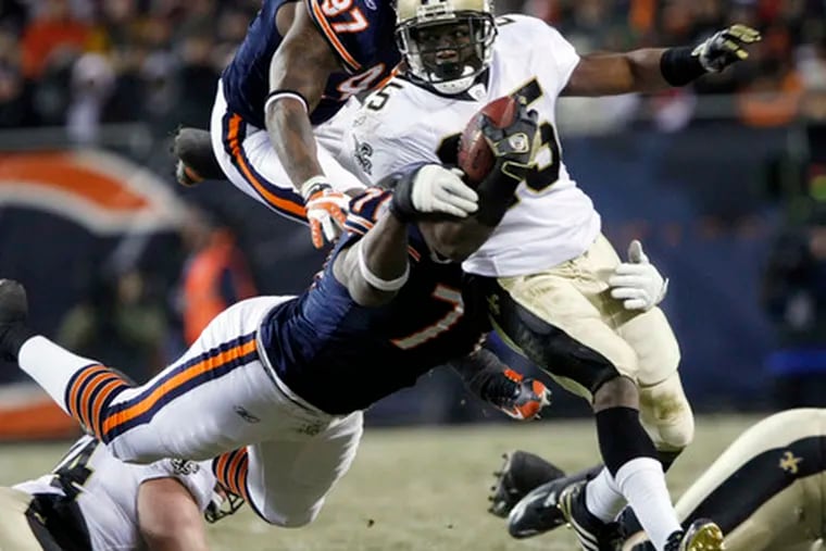 New Orleans running back Reggie Bush is grabbed by Chicago defenders Israel Idonije (71) and Mark Anderson (97) in last night&#0039;s game between the Saints and the Bears in Chicago. The Bears had a 21-7 lead at the half. The game ended too late for this edition.