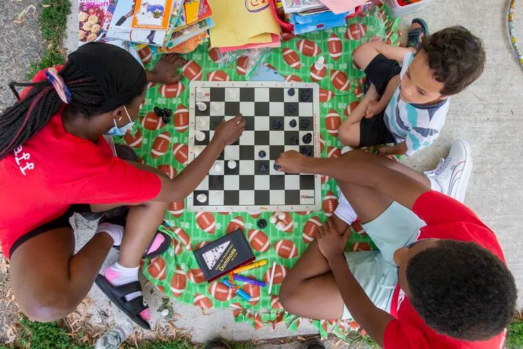 From left Keyannah Jefferson, 17, of W. Kensington, Jacob Rapier Siahaan, 6, of Norris Square Park and Semaj Harris, 16, of West Philadelphia play a game of chess July 14, 2021.