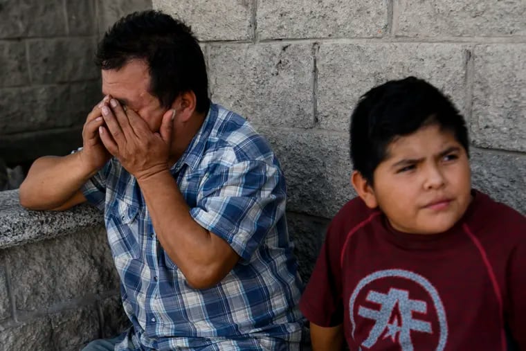 Julio Alberto Lopez cries as he sits with his son Abner, 14, near the U.S. border shortly after being returned to Ciudad Juarez, Mexico.