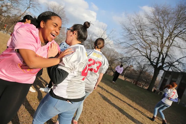 Central powderpuff football teammates Trinity Osbourne (left) and DeMadelye Navarro laugh as they execute a block at a recent gathering of the team.