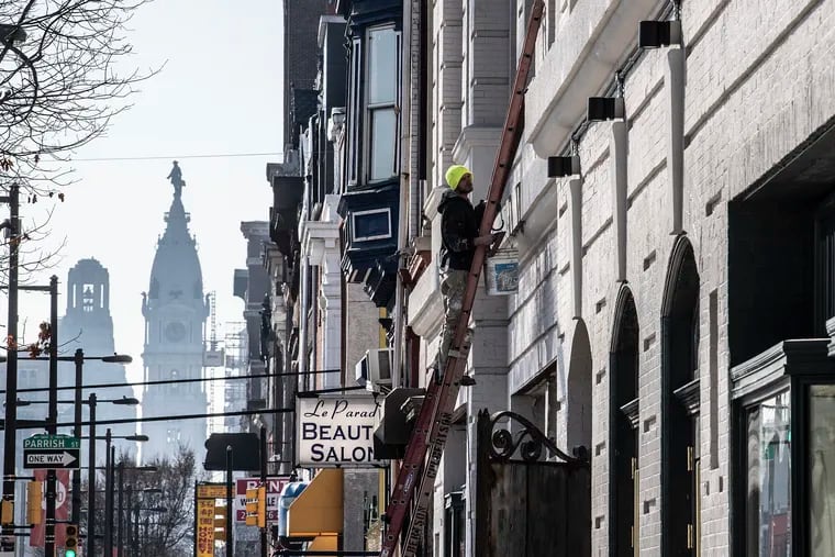 A construction crew works near the intersection of Broad Street and Girard Avenue, with City Hall in the distance. Experts expect more construction to occur on North Broad as a result of the new Opportunity Zones located along the corridor.