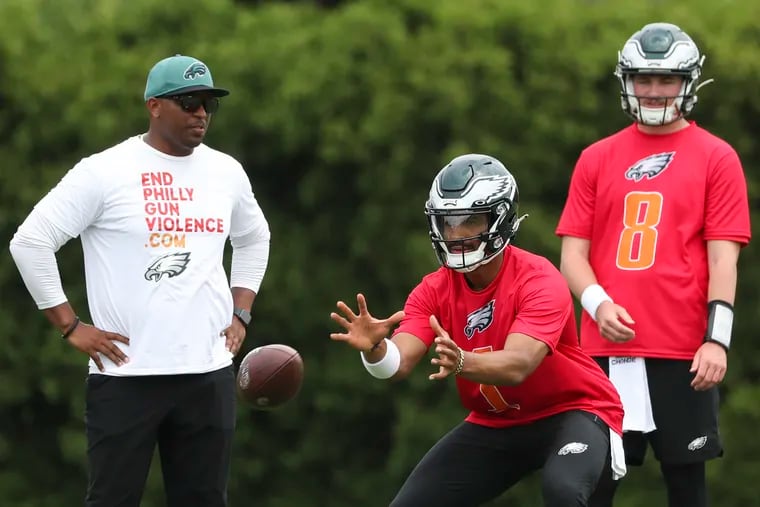 Eagles quarterback Jalen Hurts (1) runs drills during OTAs with quarterbacks coach Brian Johnson and rookie Carson Strong (8) at the NovaCare Complex in South Philadelphia on Friday, June 3, 2022.