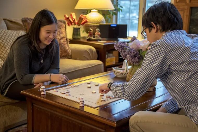 Lauren and Andrew Chen play Xiangqi (or Chinese chess) in the living room of their Moorestown home. Their parents, Teresa and Peter, are committed to preserving their Chinese heritage for their American-born children.