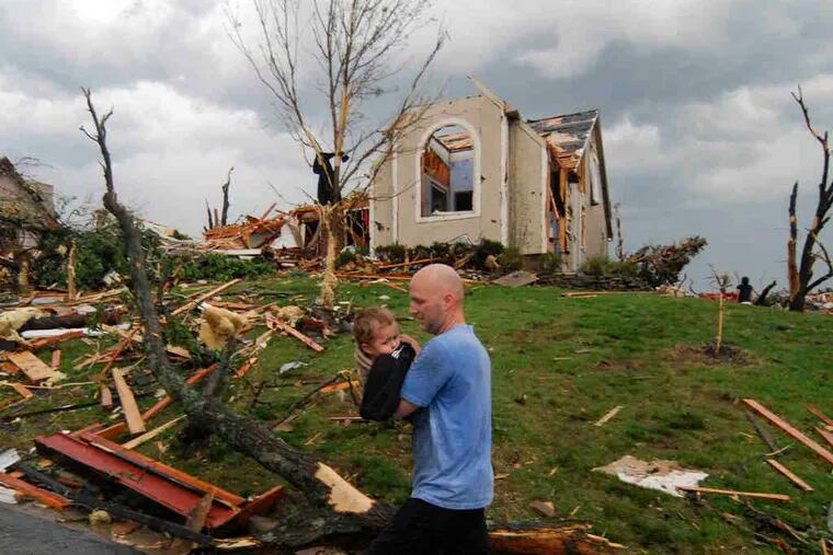 A man carries a young boy rescued after being trapped in his home in Joplin, Mo. The tornado, at times three-quarters of a mile wide, did some of its most startling damage at St. John's Regional Medical Center, where five patients and one visitor died.
